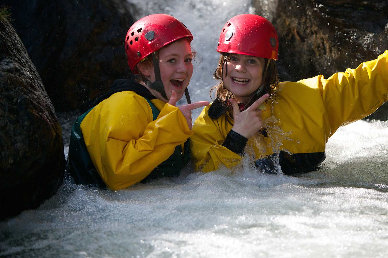 Happy teenage pupils posing in a waterfall in the gorge