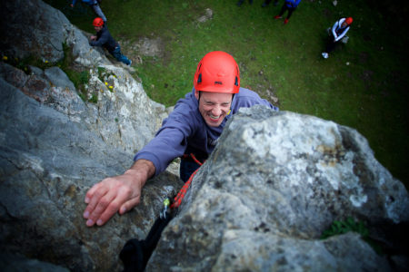 A climber, gritting his teeth, trying to reach the top of the crag 